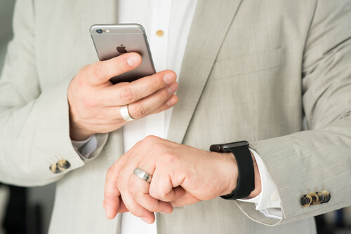 Businessman is checking his Apple Watch while using his iPhone 6 - Hire intelligence