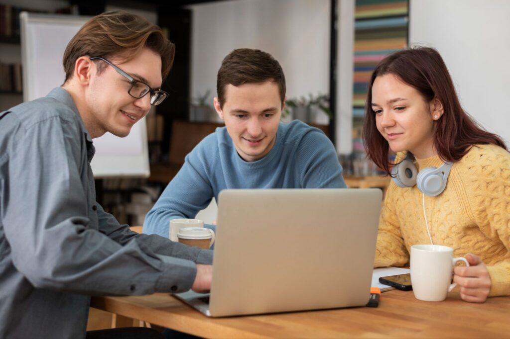 Three colleagues sitting at a desk and working together on a MacBook Air M5