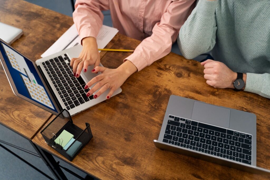 Two professionals working on rented MacBooks at a desk.